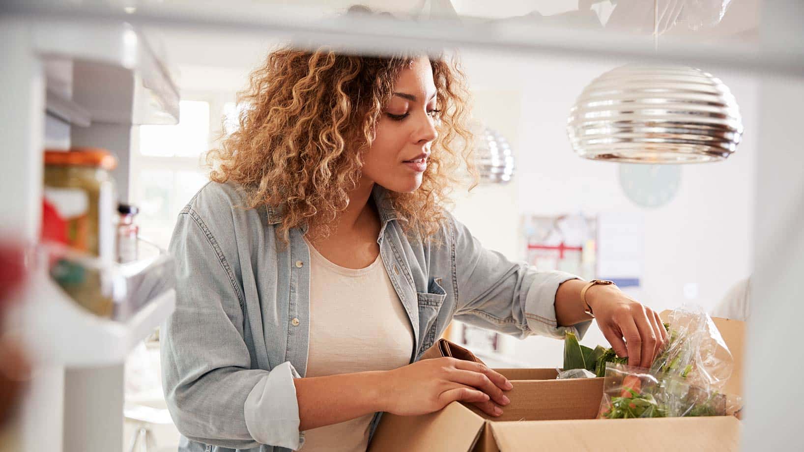 Eine Frau räumt Lebensmittel, die sie über den Online-Handel bestellt hat, in ihren Kühlschrank ein.