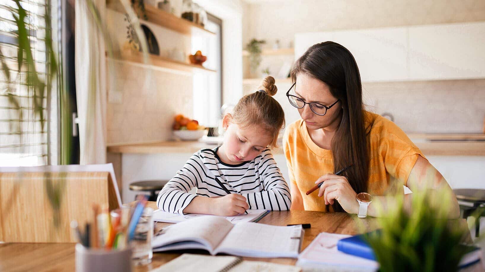 Eine Mutter schaut ihrem Kind beim Lernen über die Schulter.